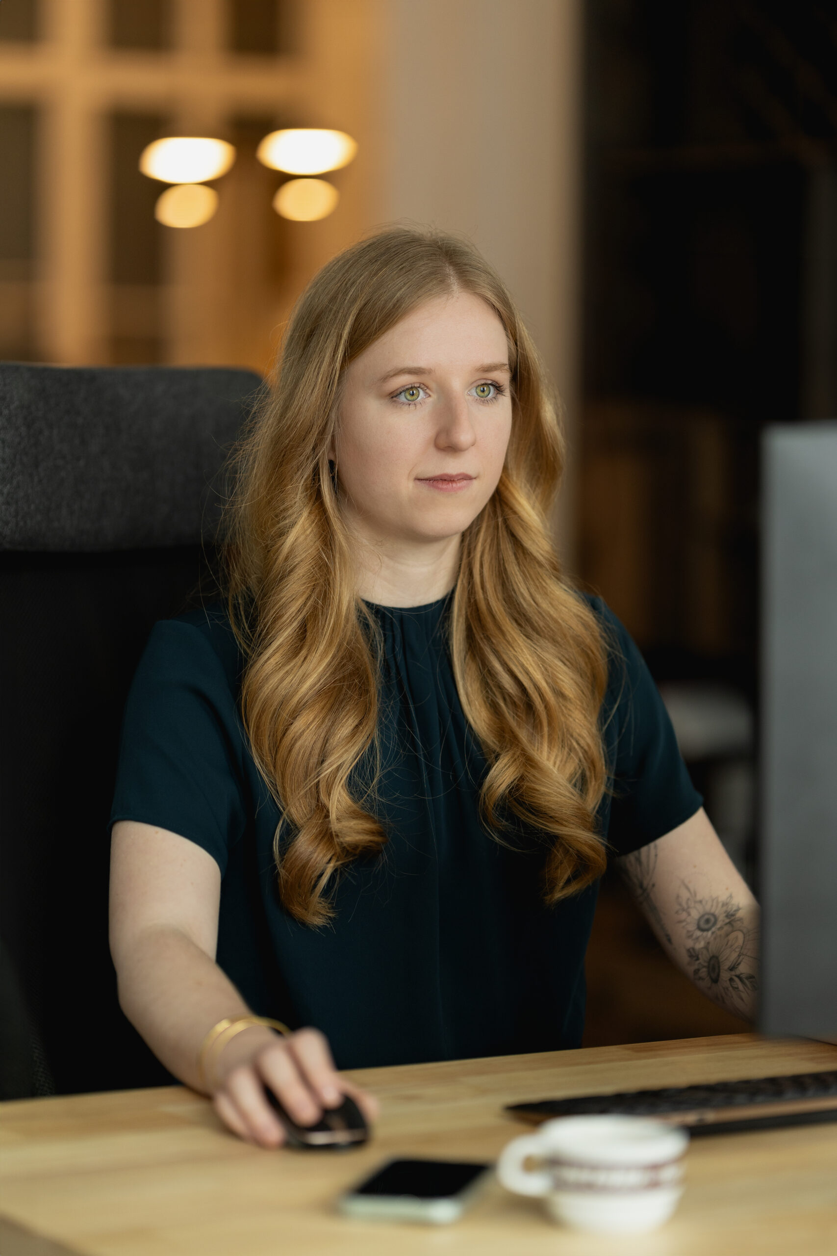 Junge rothaarige Frau sitzt am Computer und arbeitet