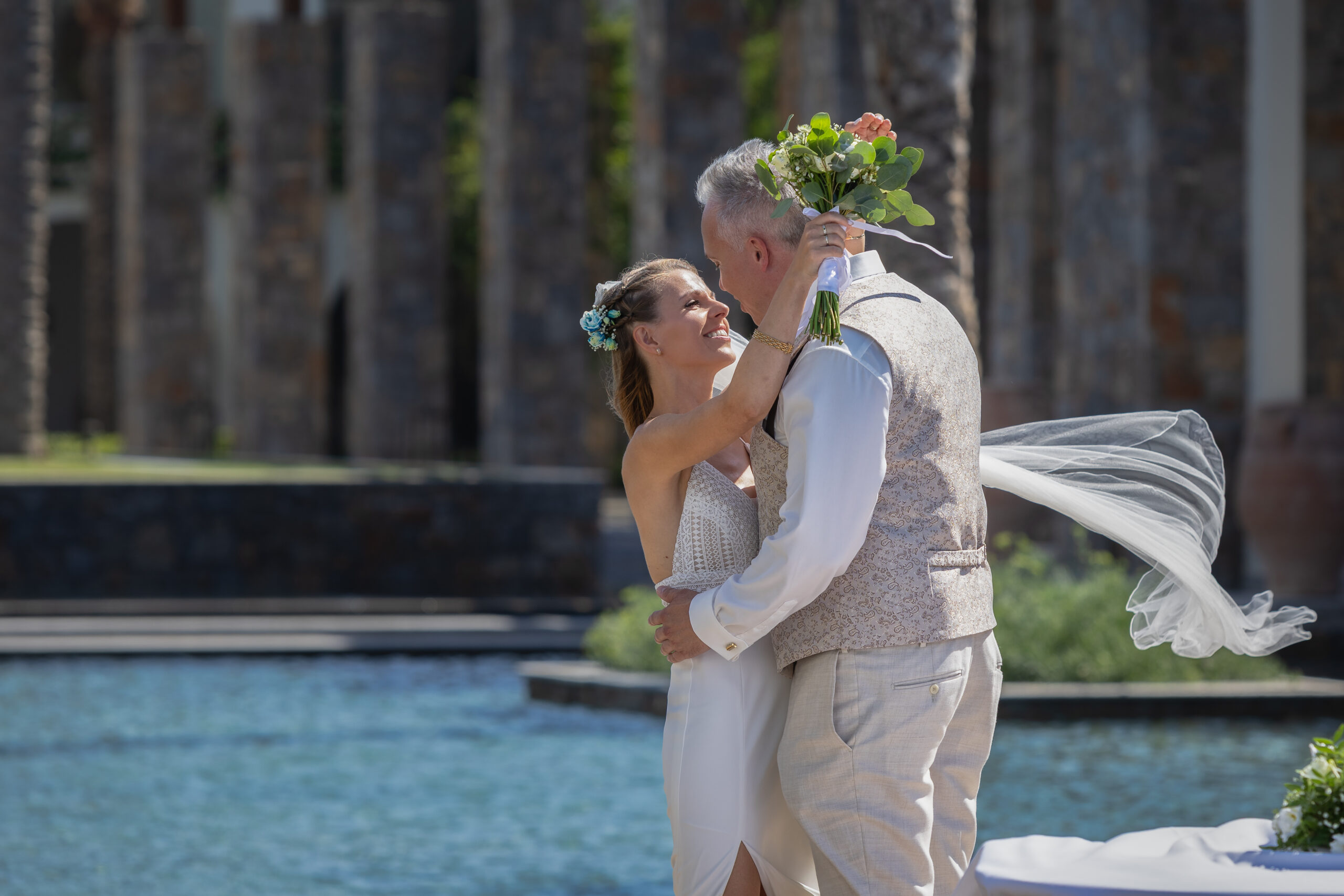 Paar umarmt sich und schaut sich gegenseitig in die Augen, Braut hält einen Blumenstrauß in der Hand